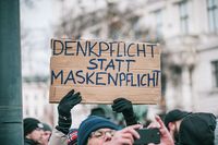 Anti-Corona-Demonstrant hält Plakat mit Botschaft Denkpflicht statt Maskenpflicht