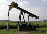 Erdölförderung in Deutschland: Pferdekopf-Pumpe auf dem ehemaligen Erdölfeld Varel. Im Hintergrund drei Windkraftanlagen