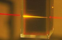 Rotes Licht eines Laserpointers wird beim Durchgang durch die Flüssigkeit des photochemischen Hochkonverters in energiereiches gelbes Licht umgewandelt.
Quelle: Foto: University of Sydney, Australien (idw)