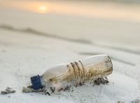Plastikflasche am Strand: viele Mikroteile im Meer.