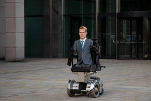 Janis McDavid im Rollstuhl vor dem Bürogebäude
